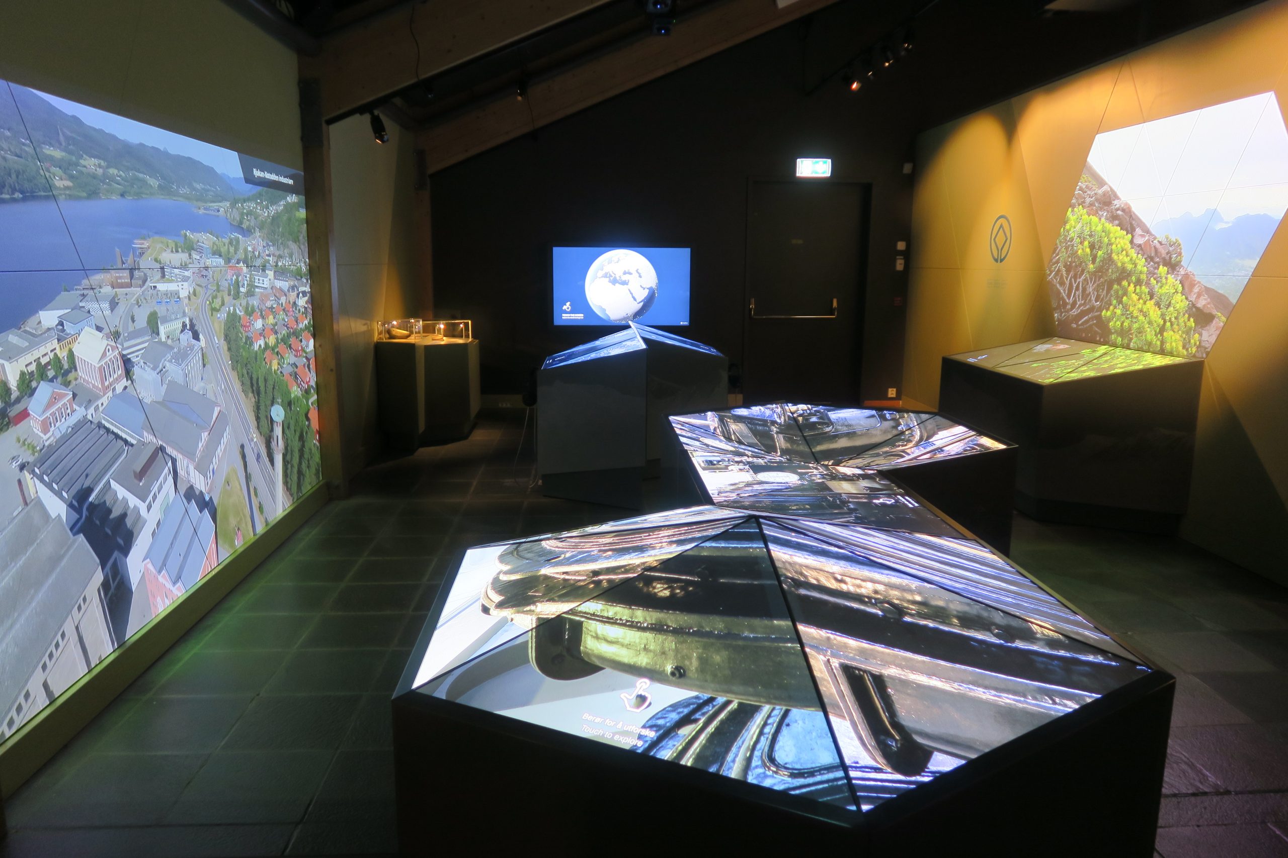 Bildet viser et mørkt rom med forskjellige skjermer i diverse formasjoner som viser et utvalg av fotografier